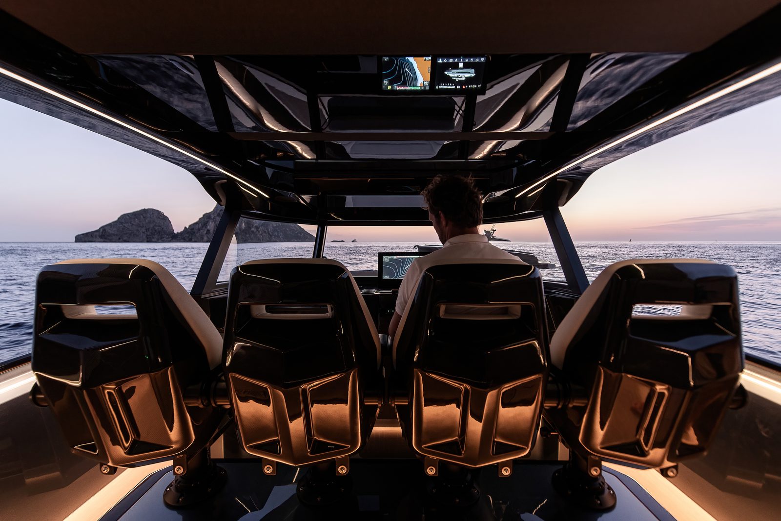 Stuurstand van een Stratos DB50 met carbon console, schipper aan het roer bij zonsondergang